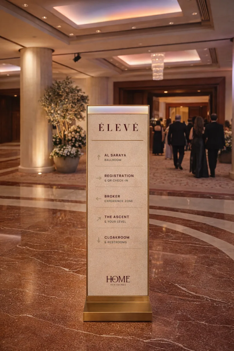 Directional signage — A limestone and brass totem pointing guests to the Ballroom, Registration, Broker Zone, The Ascent and Cloakroom
